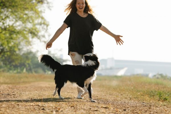 Eine Frau und ihr Hund laufen glücklich auf einem Feldweg